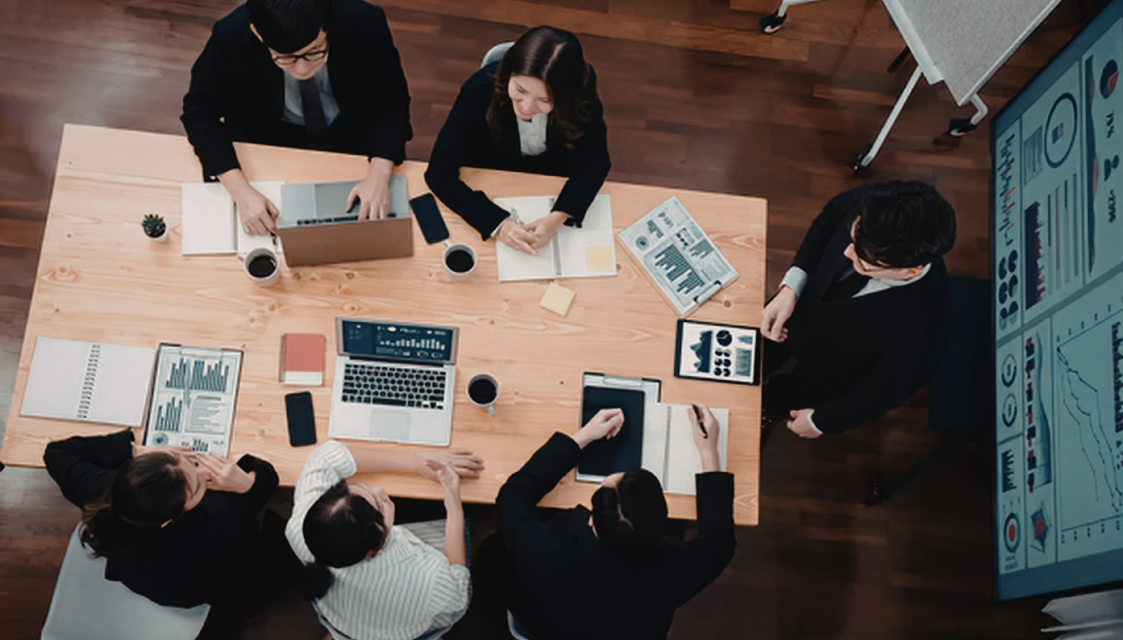 Sales team gathered around a table comparing conference notes
